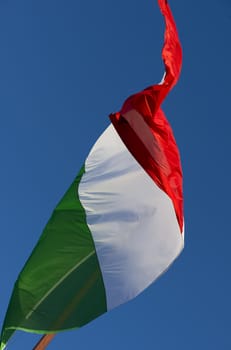 A large Italian flag in the blue sky free