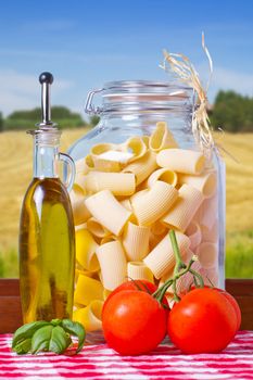 Typical Italian pasta inside a glass jar, with tomatoes and basil