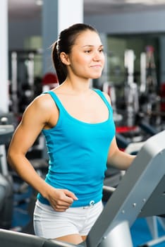 young woman running on a treadmill, exercise at the fitness club