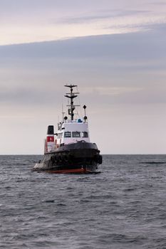 Powerful tug-boat with high bows for pushing or pulling cargo or marine vessels floating in wait on calm ocean at anchor
