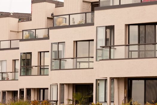 External facade of contemporary residential apartment block development with large glass windows and balconies for every unit.