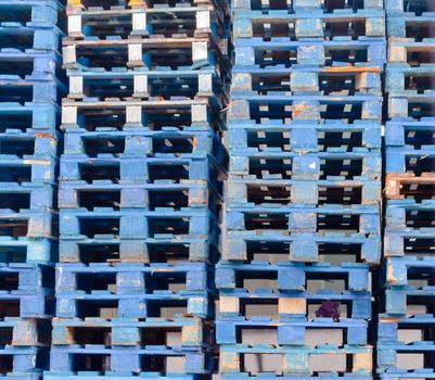Stack of piled blue rough wooden euro pallets background texture pattern