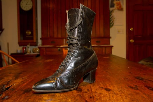 A very old vintage boot photographed on an antique table.