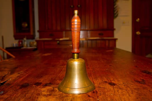 An old bell for ringing photographed on a vintage antique wooden table.