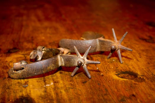 A set of old antique metal stirrups photographed on a wooden dining table.