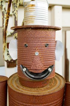 A tin man is made out of old rusty cans and he is smiling at the camera.