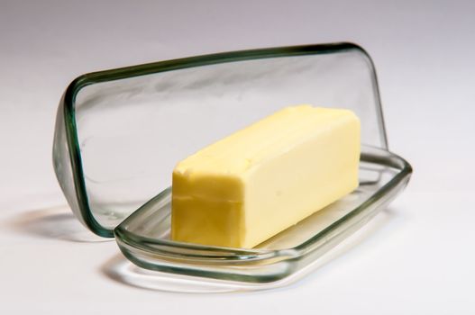 Clear glass butter dish with   stick of butter