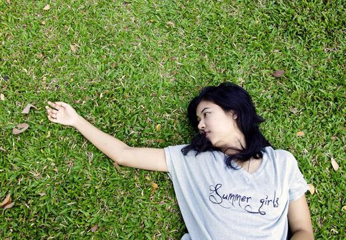Young asian woman laying in the grass with a lot of space
