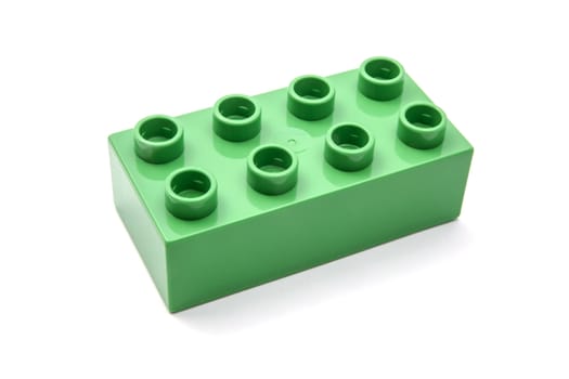 Green building block closeup on white background 