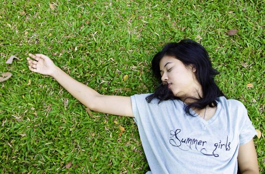 Young beautiful asian laying on the grass, in the park