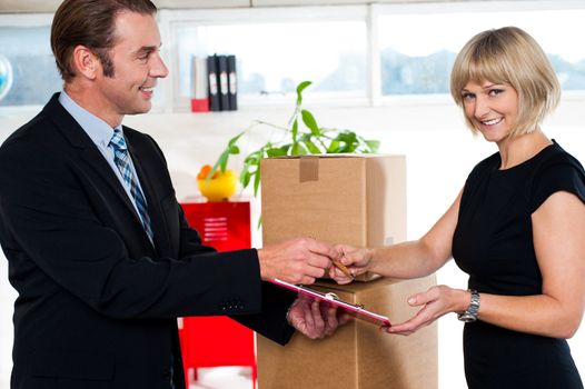 Man handing over business papers of goods delivered in order to get them signed by his casual boss.
