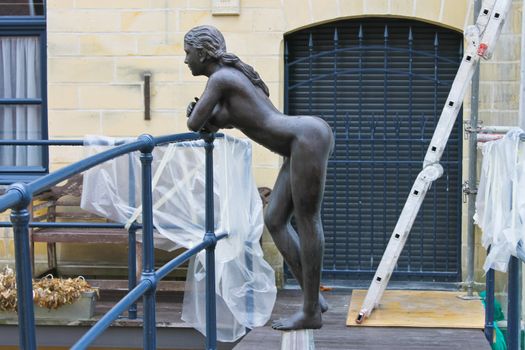Statue of a naked girl leaning on the railing of the bridge