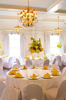 Place settings, tables, and chairs are empty before the guests arrive at a wedding reception.