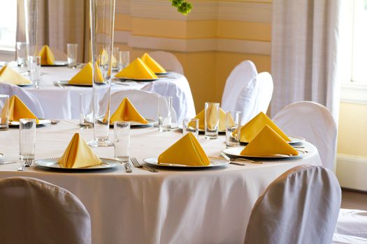 Place settings, tables, and chairs are empty before the guests arrive at a wedding reception.