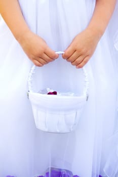 A flowergirl at a wedding holds her basket of flowers right before the ceremony starts.