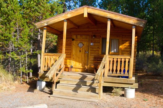 A rustic log cabin lodge building in the woods at an outdoors camping park facility.