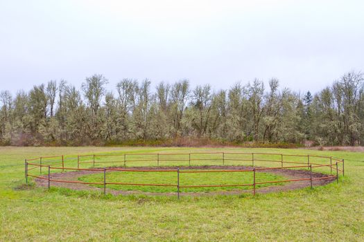 A horse training circle corral outdoors on teh grass at an equestrian center.