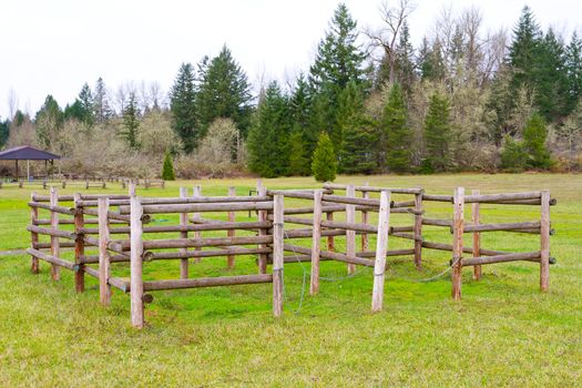An equestrian center has horse training stalls outdoors on the grass.