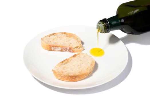 Sliced bread with olive oil being poured on a white plate, isolated on white background