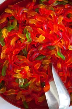 Gummy worms are together in a serving dish at a candy buffet at a wedding.