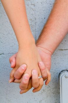 A man and a woman holding hands with their fingers interlocked.