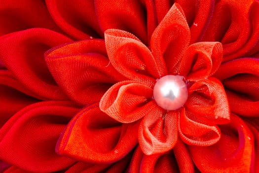 A bright red flower sewn from fabric at a wedding.