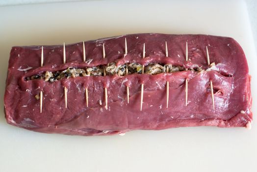 beef stuffed with mushroom filling ready to be laced using a string between the toothpicks