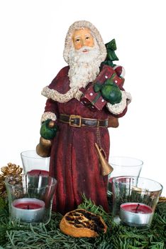Advent wreath with burning red candles and Santa Claus figure in the centre