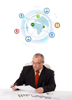 businessman sitting at desk with a globe and social icons, isolated on white