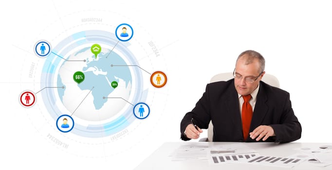 businessman sitting at desk with a globe and social icons, isolated on white