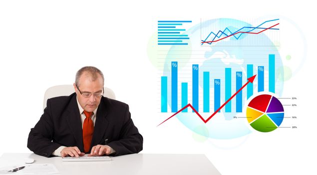 Businessman sitting at desk with statistics, isolated on white