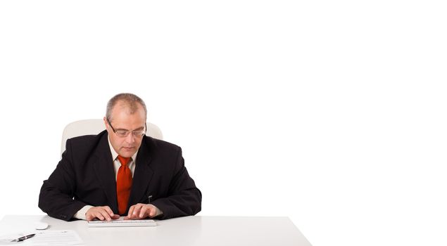 businessman sitting at desk and typing on keyboard with copy scape, isolated on white