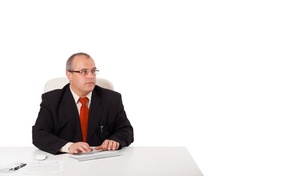 businessman sitting at desk and typing on keyboard with copy scape, isolated on white