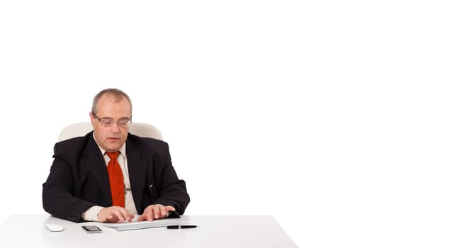 businessman sitting at desk and typing on keyboard with copy scape, isolated on white