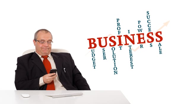 businessman sitting at desk and holding a mobilephone with business word cloud, isolated on white