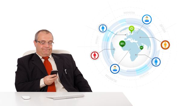businessman sitting at desk and holding a mobilephone with globe and social icons, isolated on white