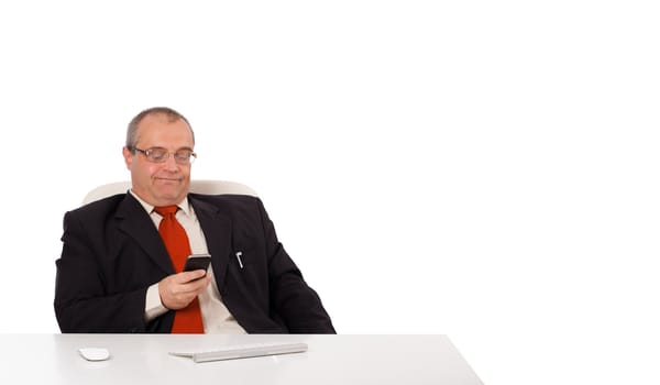 businessman sitting at desk and holding a mobilephone with copys pace, isolated on white