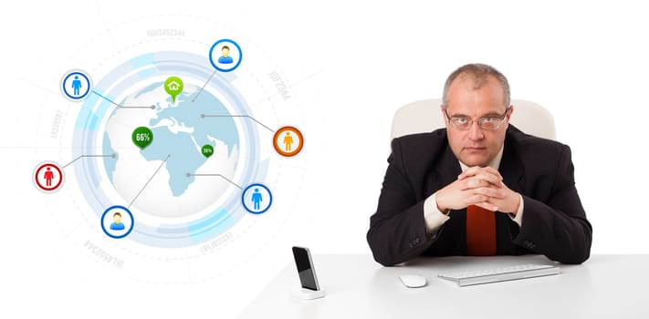 businessman sitting at desk with a globe and social icons, isolated on white