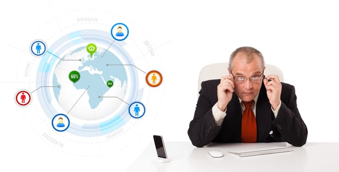 businessman sitting at desk with a globe and social icons, isolated on white