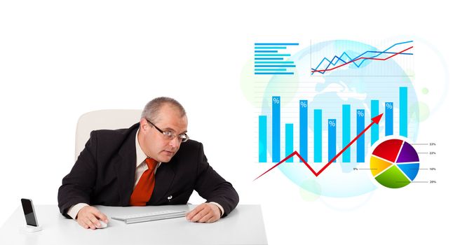 Businessman sitting at desk with statistics, isolated on white