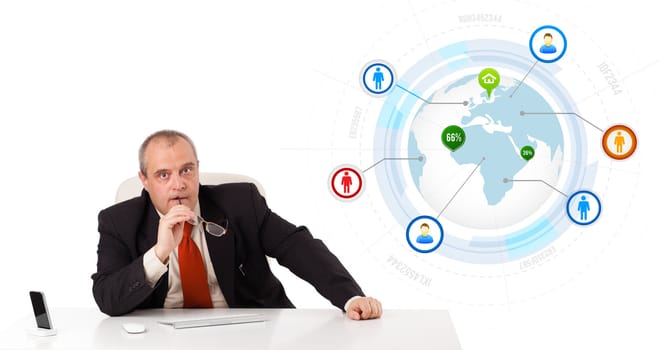 businessman sitting at desk with a globe and social icons, isolated on white