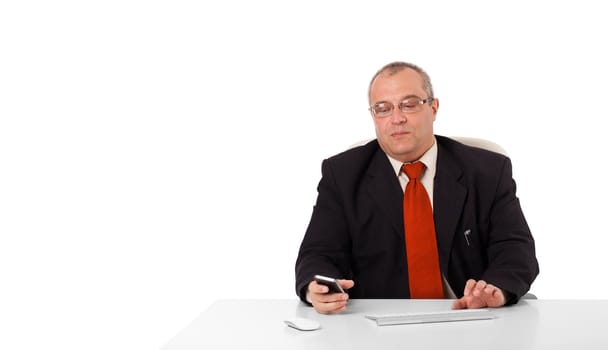 businessman sitting at desk and holding a mobilephone with copys pace, isolated on white