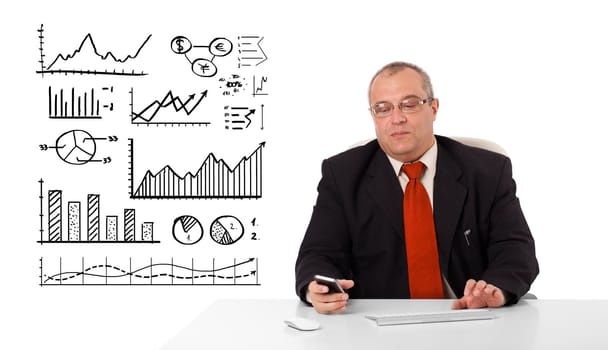 Businessman sitting at desk with diagrams and holding a mobilephone, isolated on white