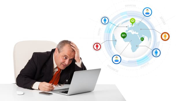 businessman sitting at desk and looking laptop with globe and social icons, isolated on white