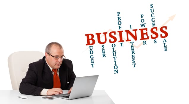 bisinessman sitting at desk and looking laptop with business word cloud, isolated on white