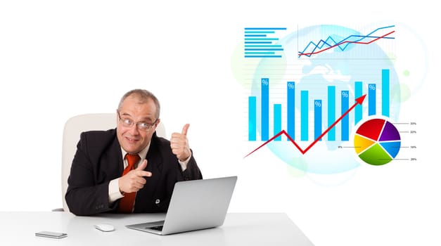 Businessman sitting at desk with laptop and statistics, isolated on white