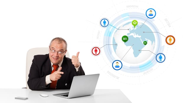 businessman sitting at desk and looking laptop with globe and social icons, isolated on white