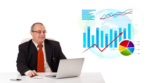 Businessman sitting at desk with laptop and statistics, isolated on white