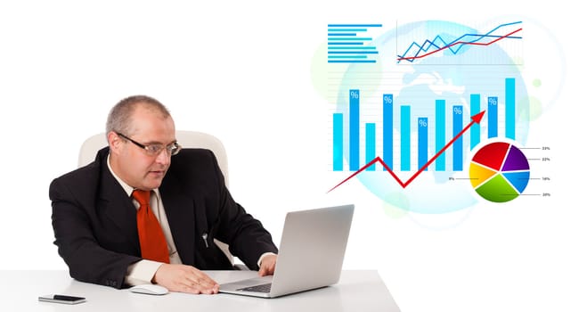 Businessman sitting at desk with laptop and statistics, isolated on white