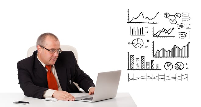 Businessman sitting at desk with diagrams and laptop, isolated on white